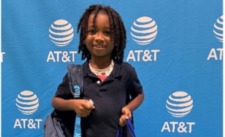 a child in front of an AT&T banner holding a bag