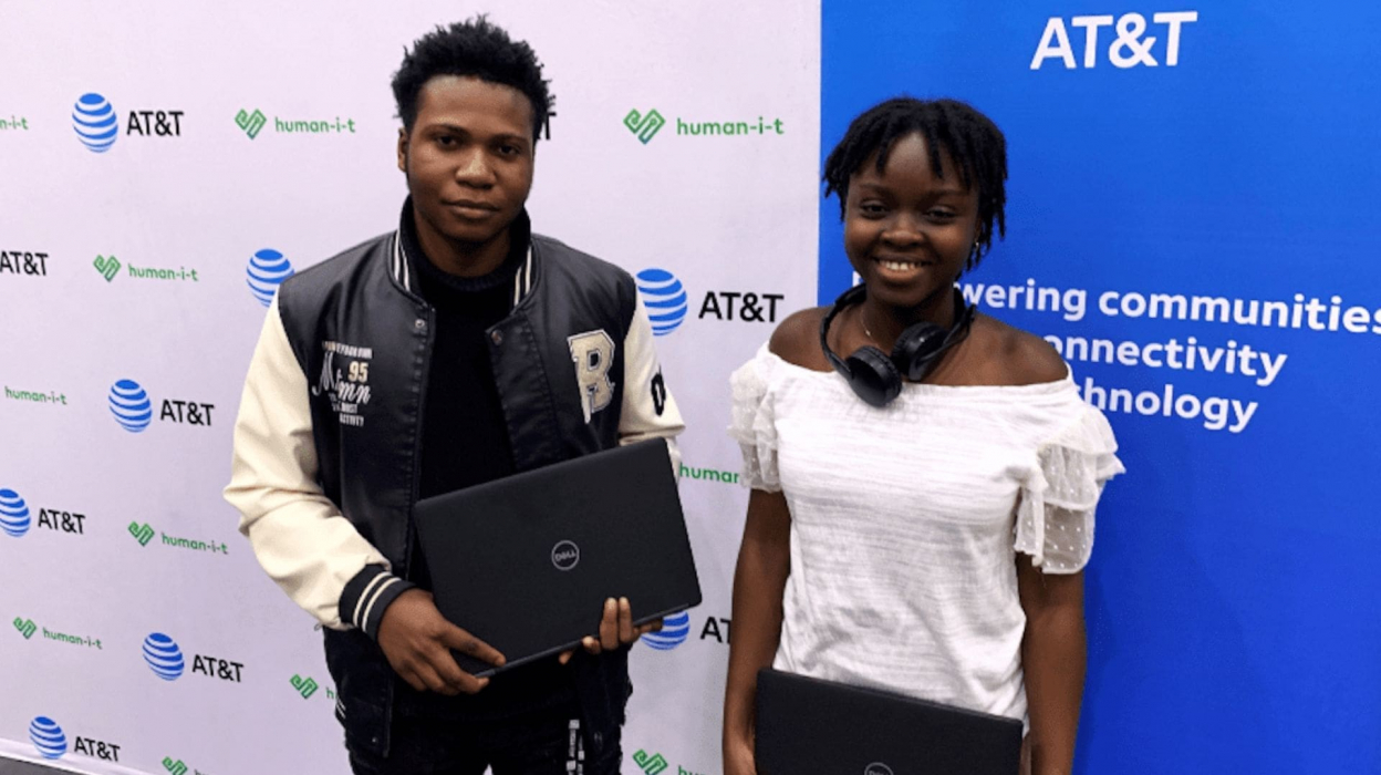 Students holding a laptop in front of an AT&T sign