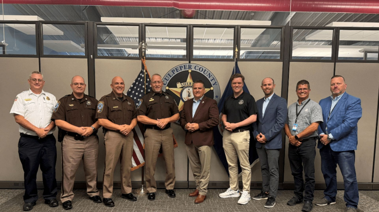 a group of nine men standing in front of the Culpepper County Sheriff's logo