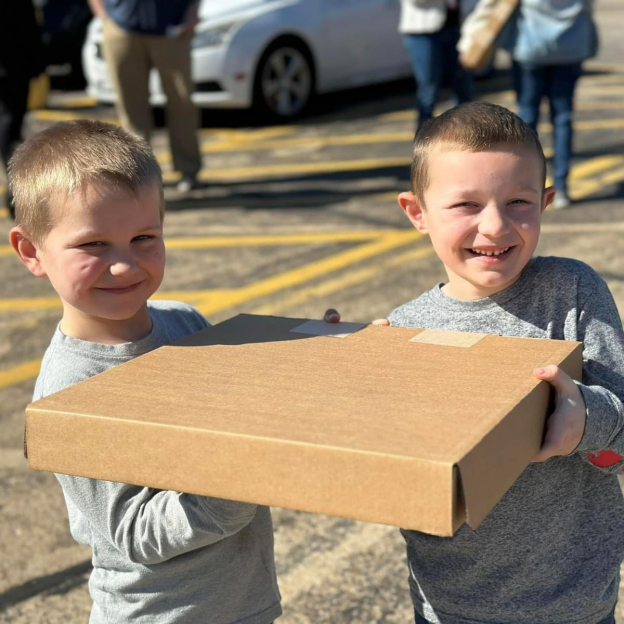 Two children, smiling, holding a box